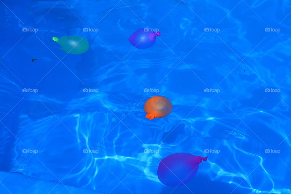 Floating water balloons. Colourful water balloons floating in swimming pool water