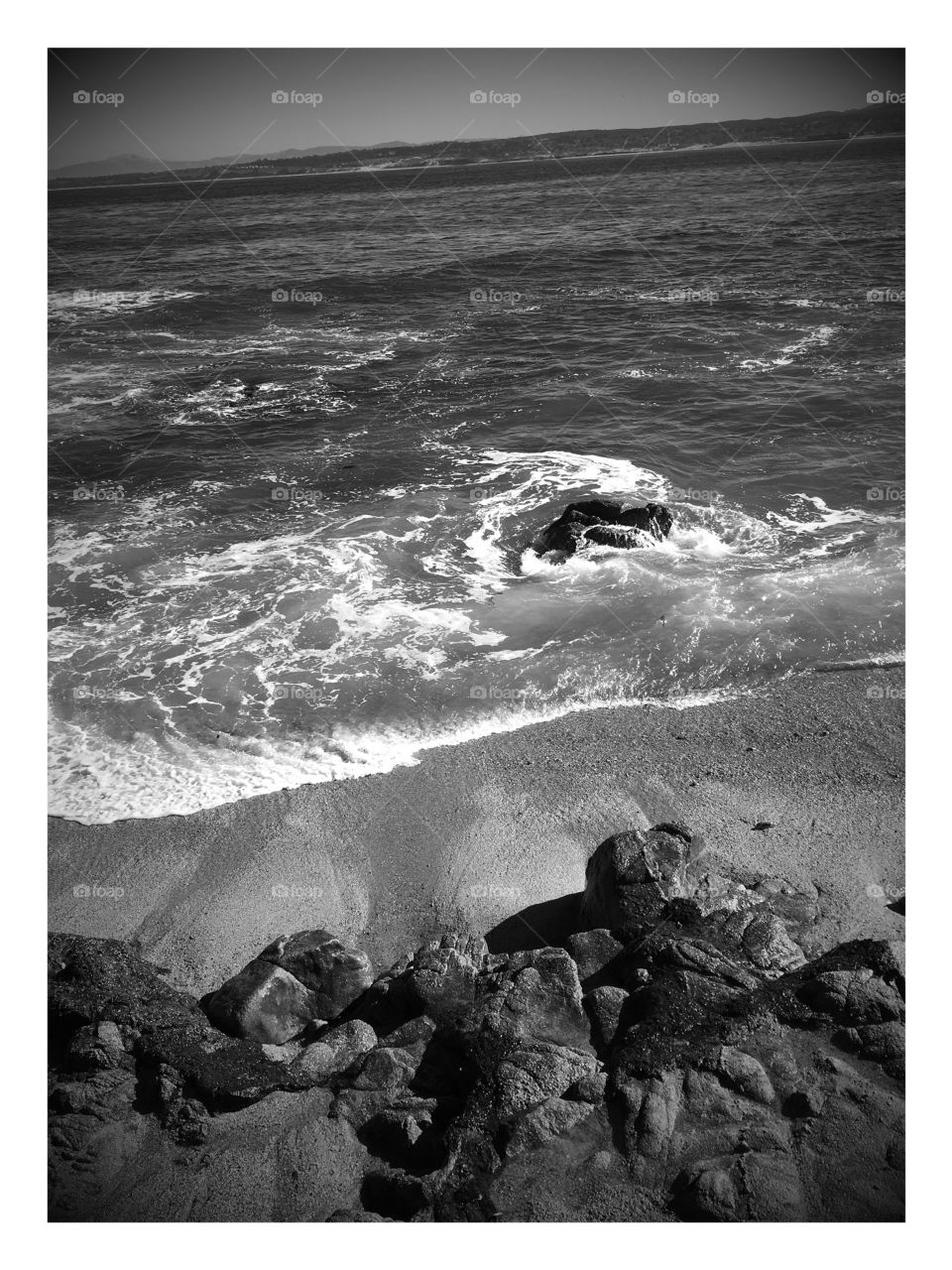 Black and white ocean landscape , waves splashing over rocks 