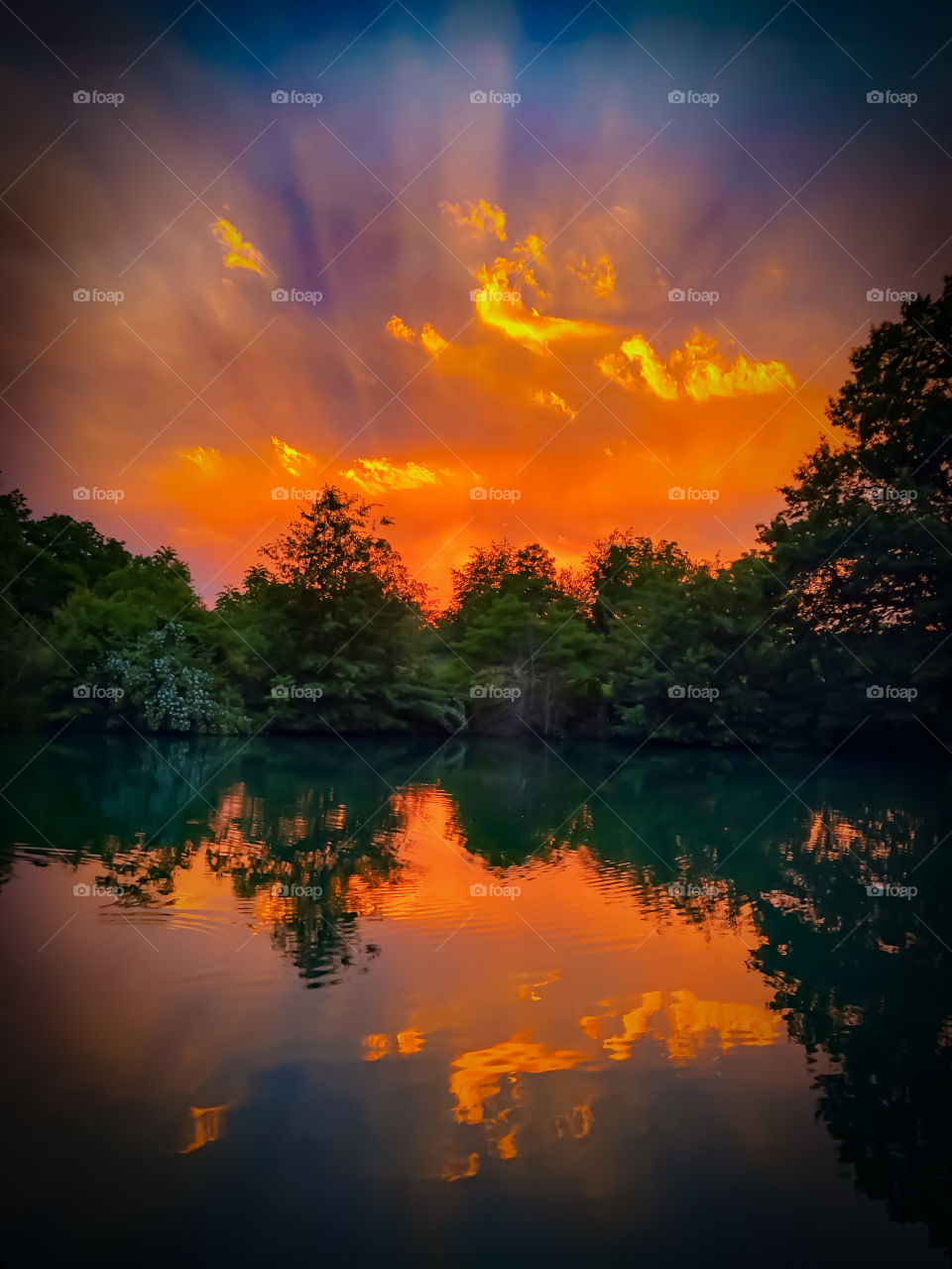 Epic Midwest prairie sunset with reflecting pond and vibrant sun-rays. 