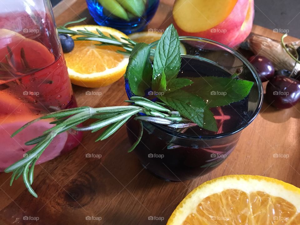 Making fresh aromatic flavored waters with  summer fruit and fresh garden herbs for aromatic refreshing drinks with peach, ginger, Rosemary, mint, cherries, orange  and blueberry 