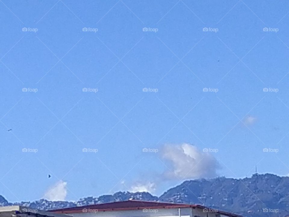 Small flakes of cloud floating over Mussoorie hills