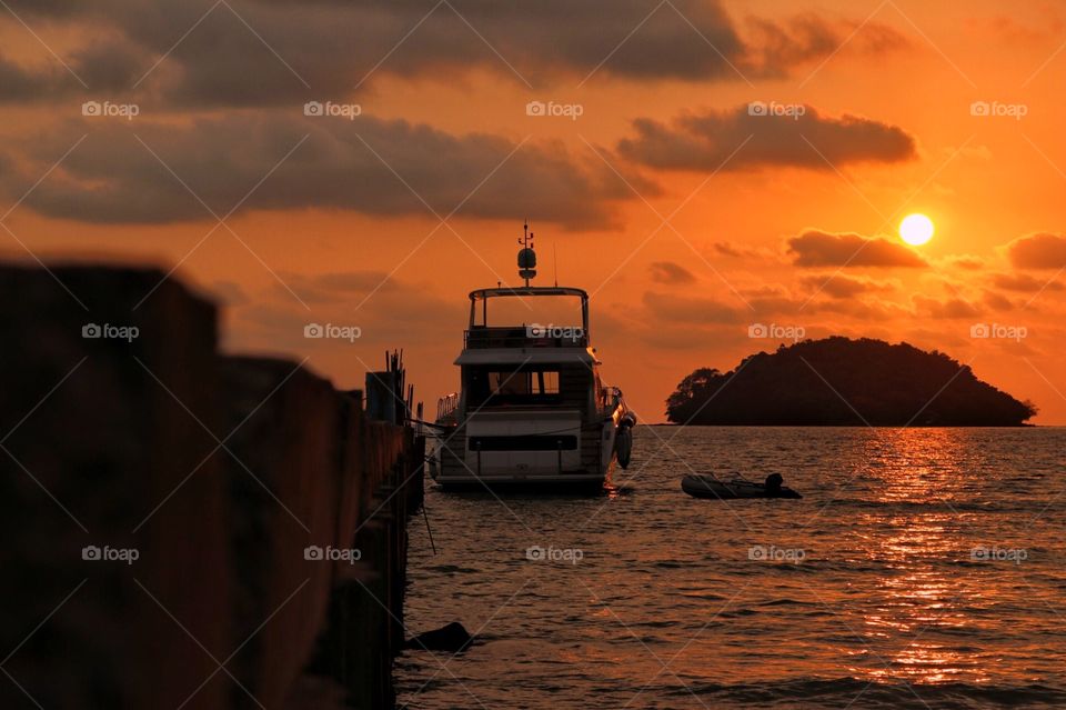 A cabin cruiser moored at Otres Beach, in Cambodia with a beautiful sunset in the background.