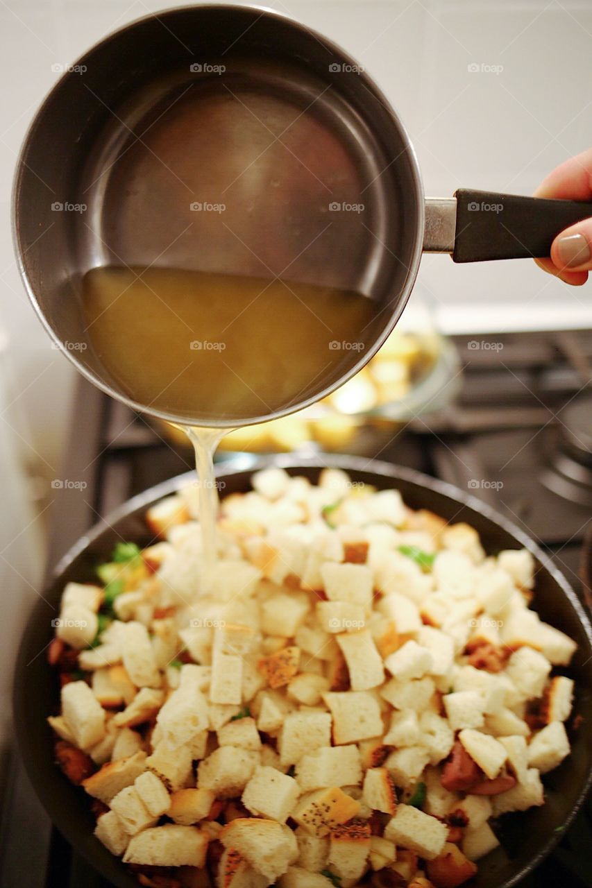 Pouring stock on the bread for stuffing 