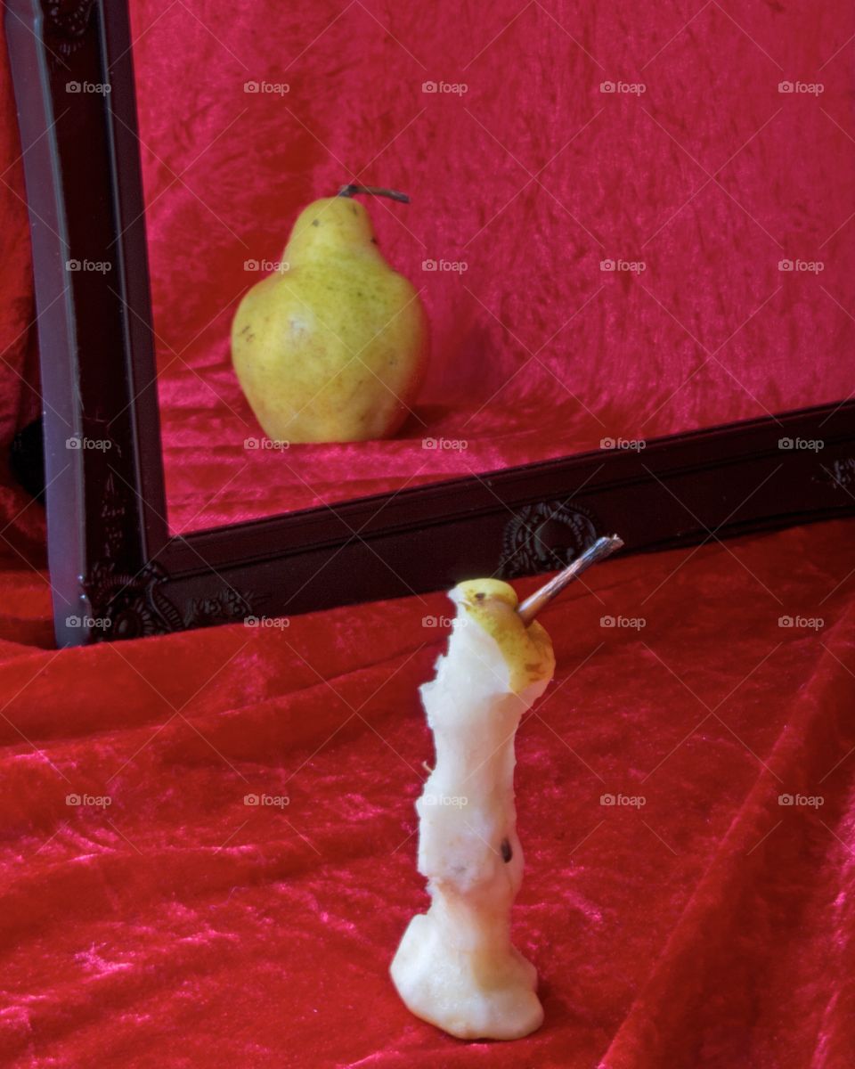 Anorexia nervosa conceptual still life with plump pear reflection from an eaten pear