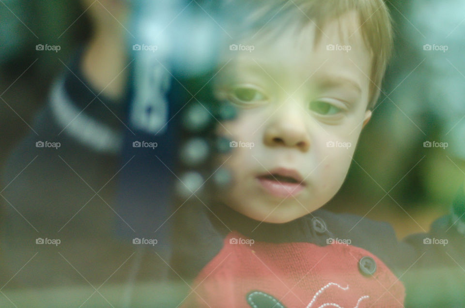Boy standing in front of transparent glass