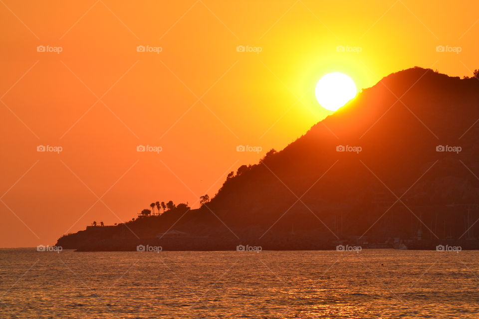 Silhouette of mountain near sea during sunset