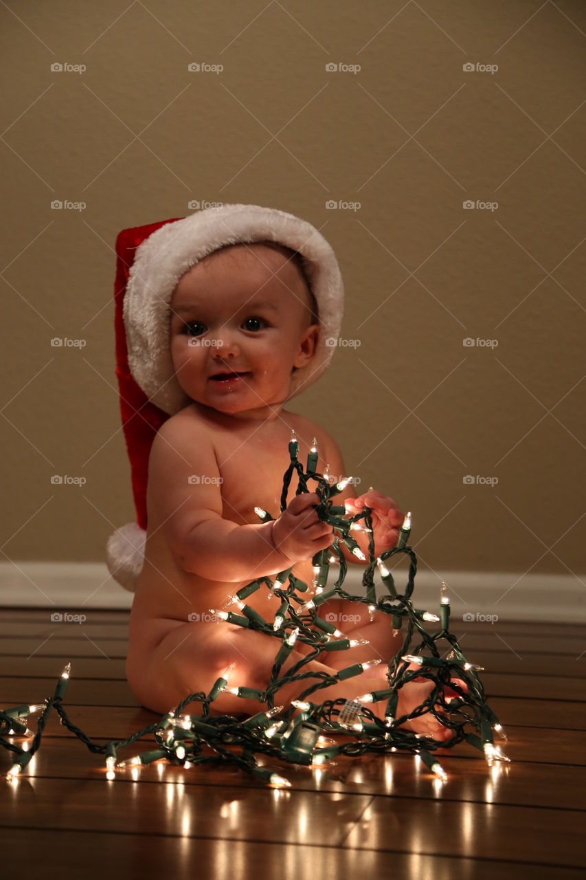 Adorable baby in christmas lights.
