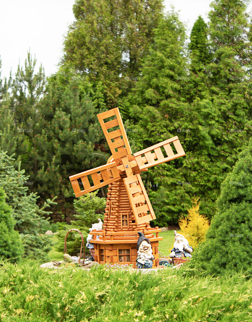 Summer garden with a decorative windmill and gnomes. European summer garden, decorative design of the site of the Baltic house