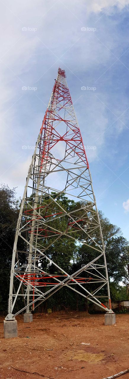 a tall cell tower in a forest. this is an Asian African type cell tower. not the kind found in North America.