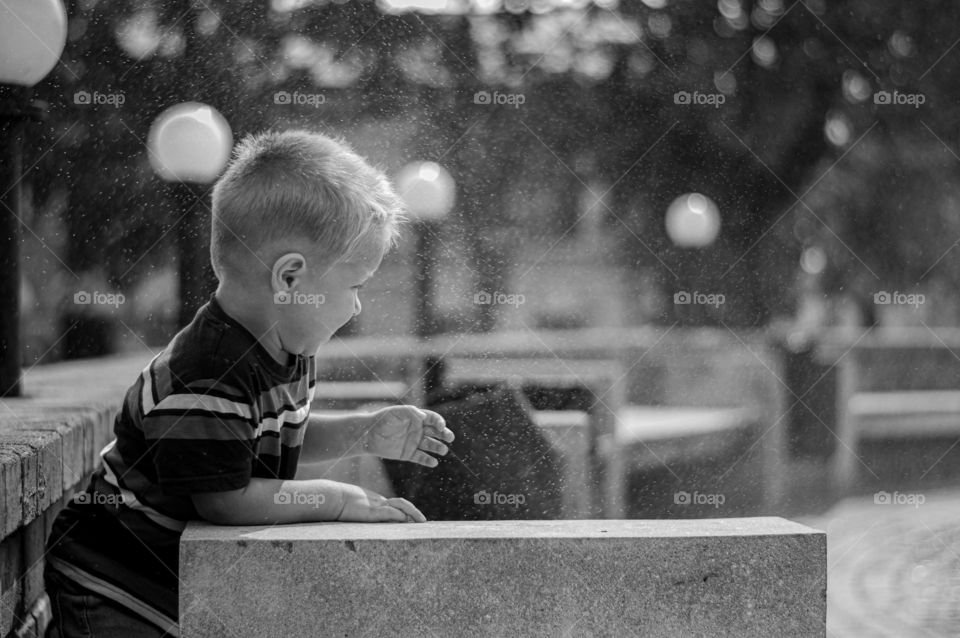 Toddler boy playing near the fountain.
