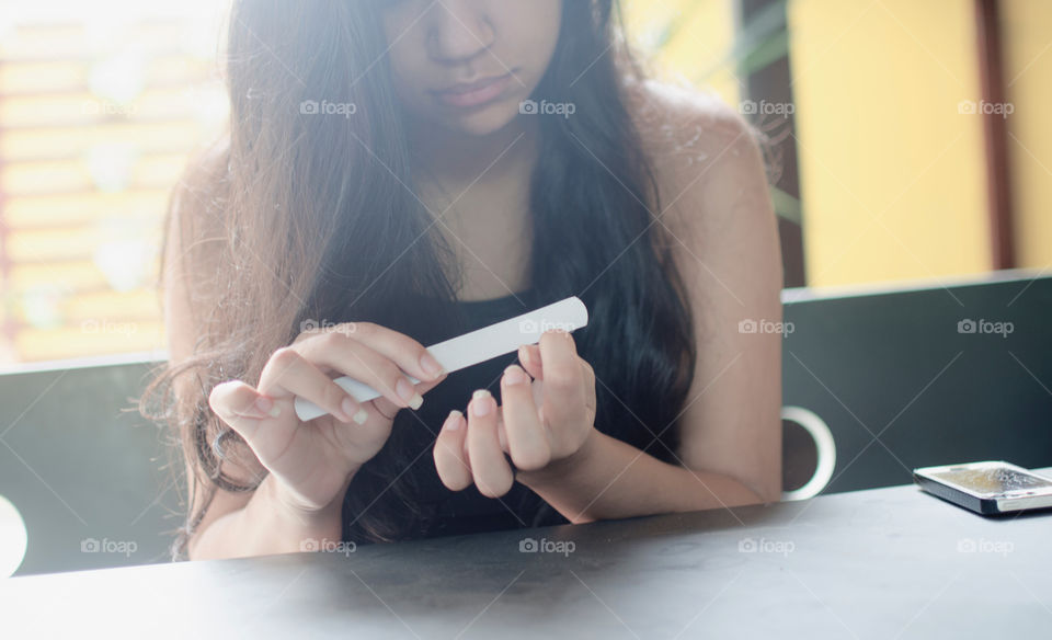 Young woman doing manicure with nail file