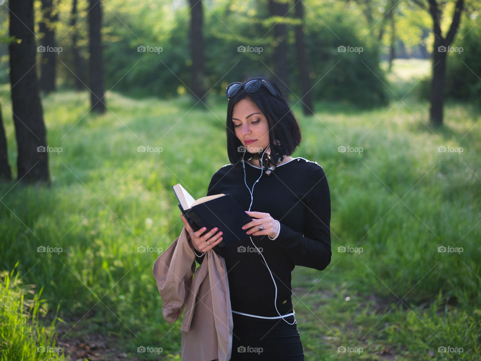 Beautiful woman reading book in the forest or park 