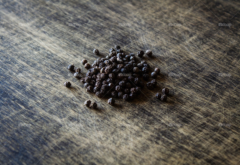 Peppercorns on a brown table. Spice.  View from above