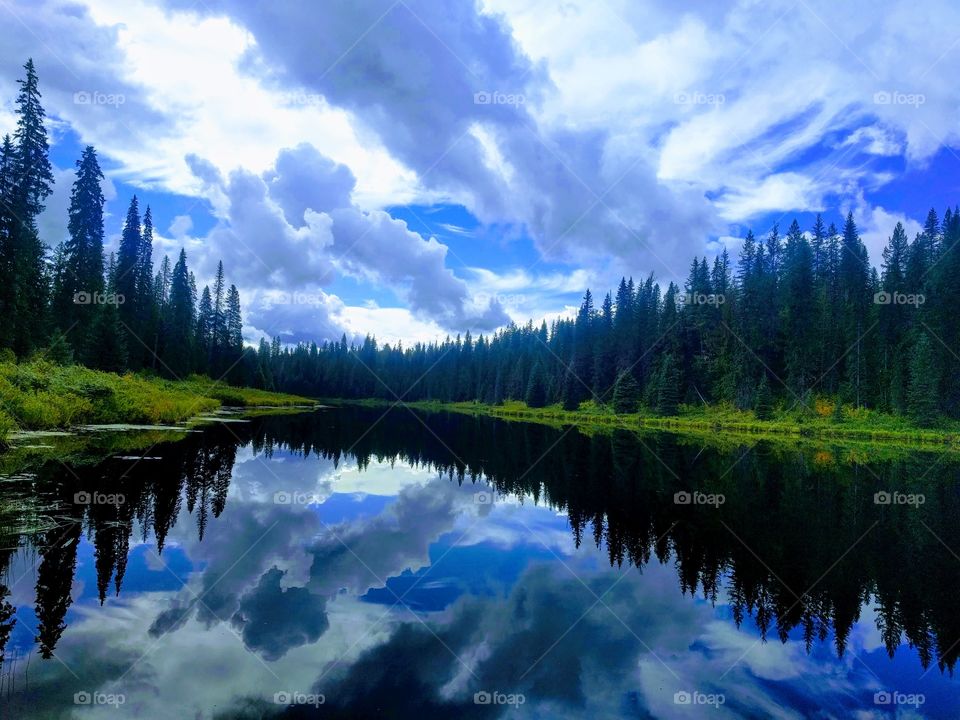Blue Sky over the mountain mirrored in a glacier lake in Canada