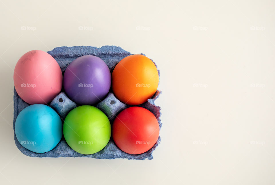 Colorful Easter eggs in a cardboard isolated on white background. Shot from above shot.