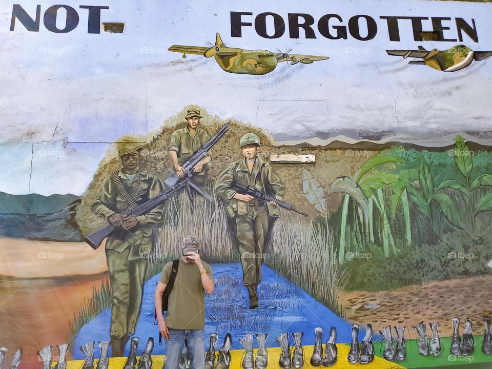 A Veteran in front of a Vietnam art mural in remembrance of Vietnam veterans.