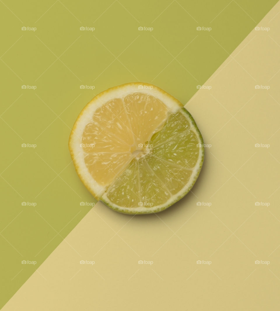 Slice of lemon and lime on contrasting color creating full circle.