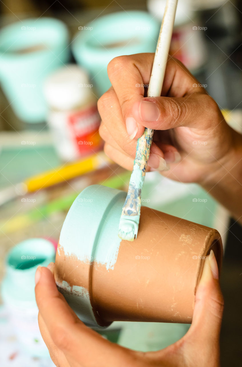 Human hand painting a flower pot