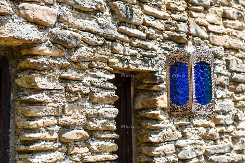 Blue glass lantern hanging in front of an old stone building