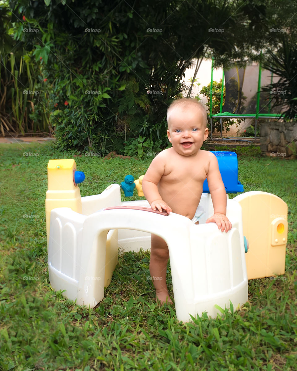 Toddler boy standing with plastic toy at backyard