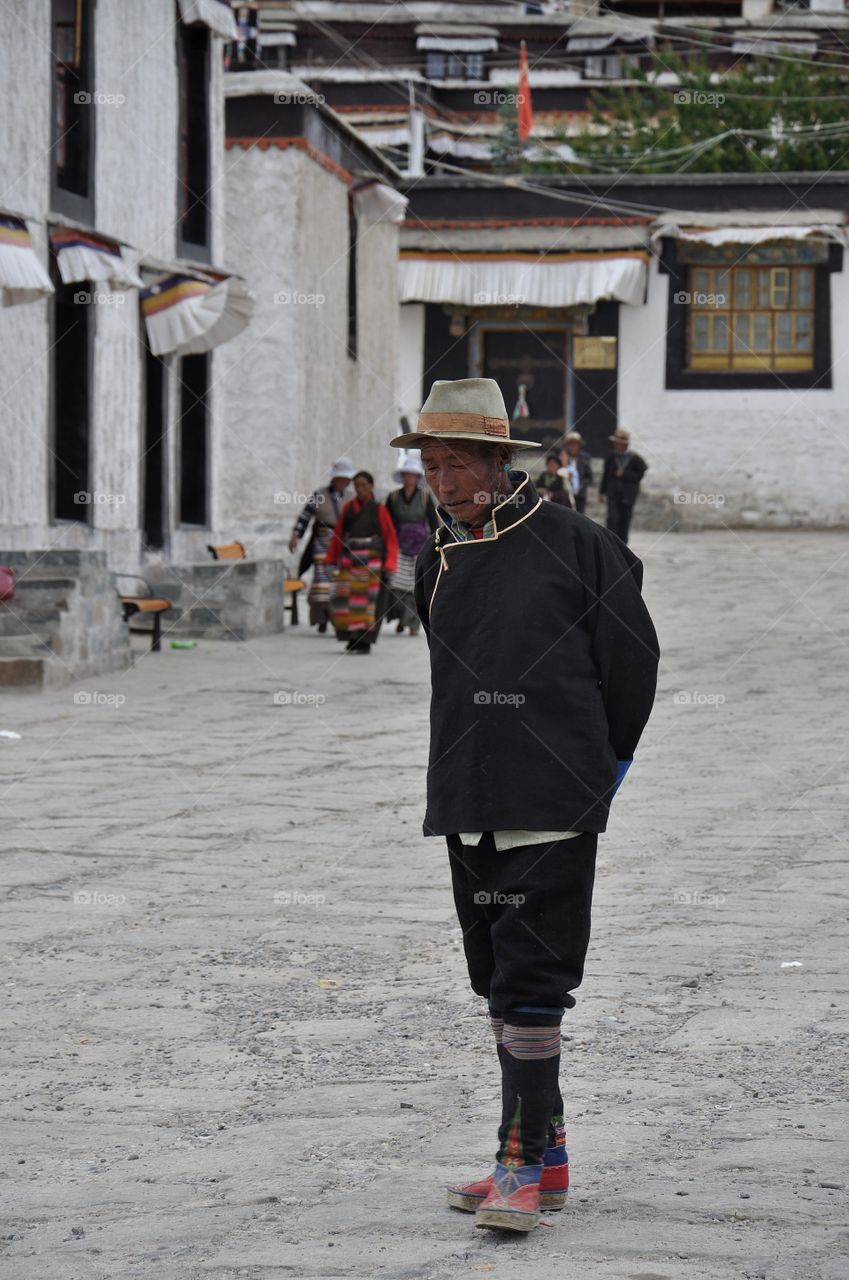 old man walking in the buddhist monastery yard in shigatse