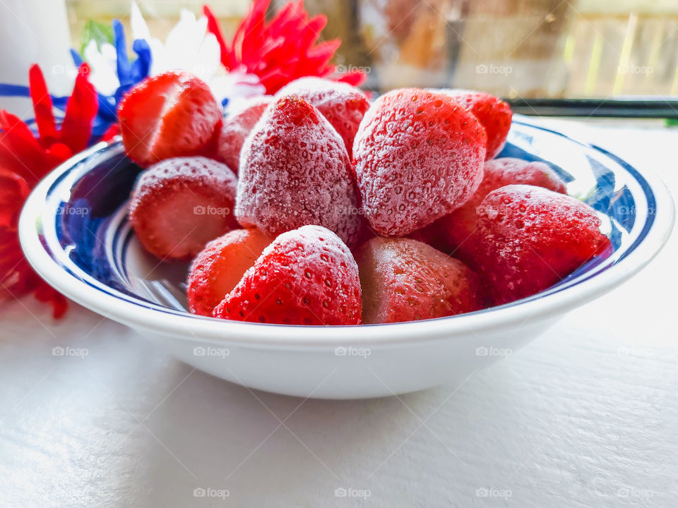 A refreshing bowl of frozen strawberries on a hot July summer day!