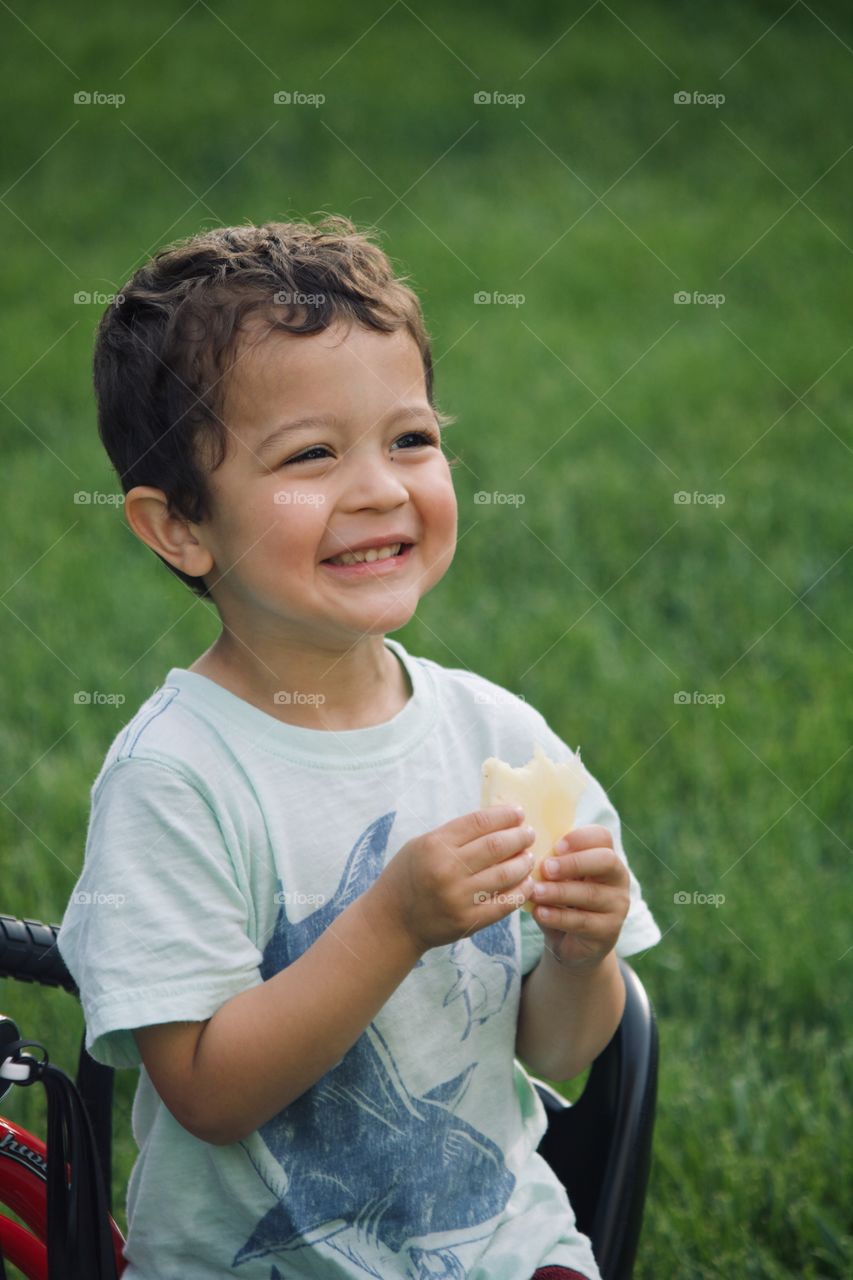 Little boy eating a slice of pineapple 