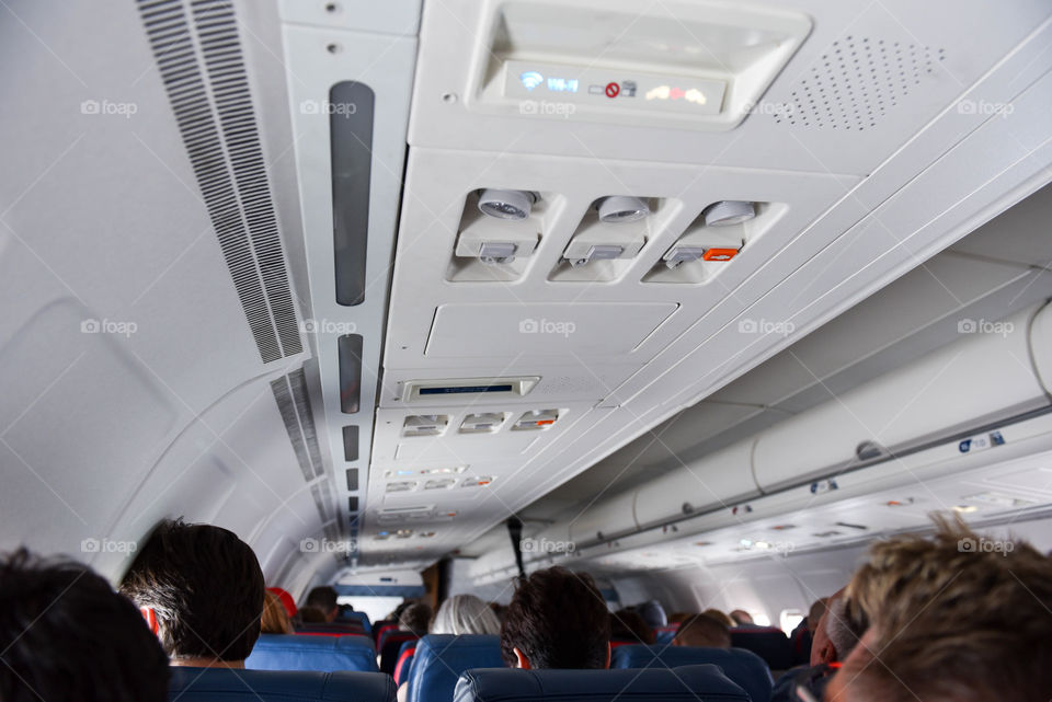 View from passenger seat on a commercial airplane of rows of other seated passengers