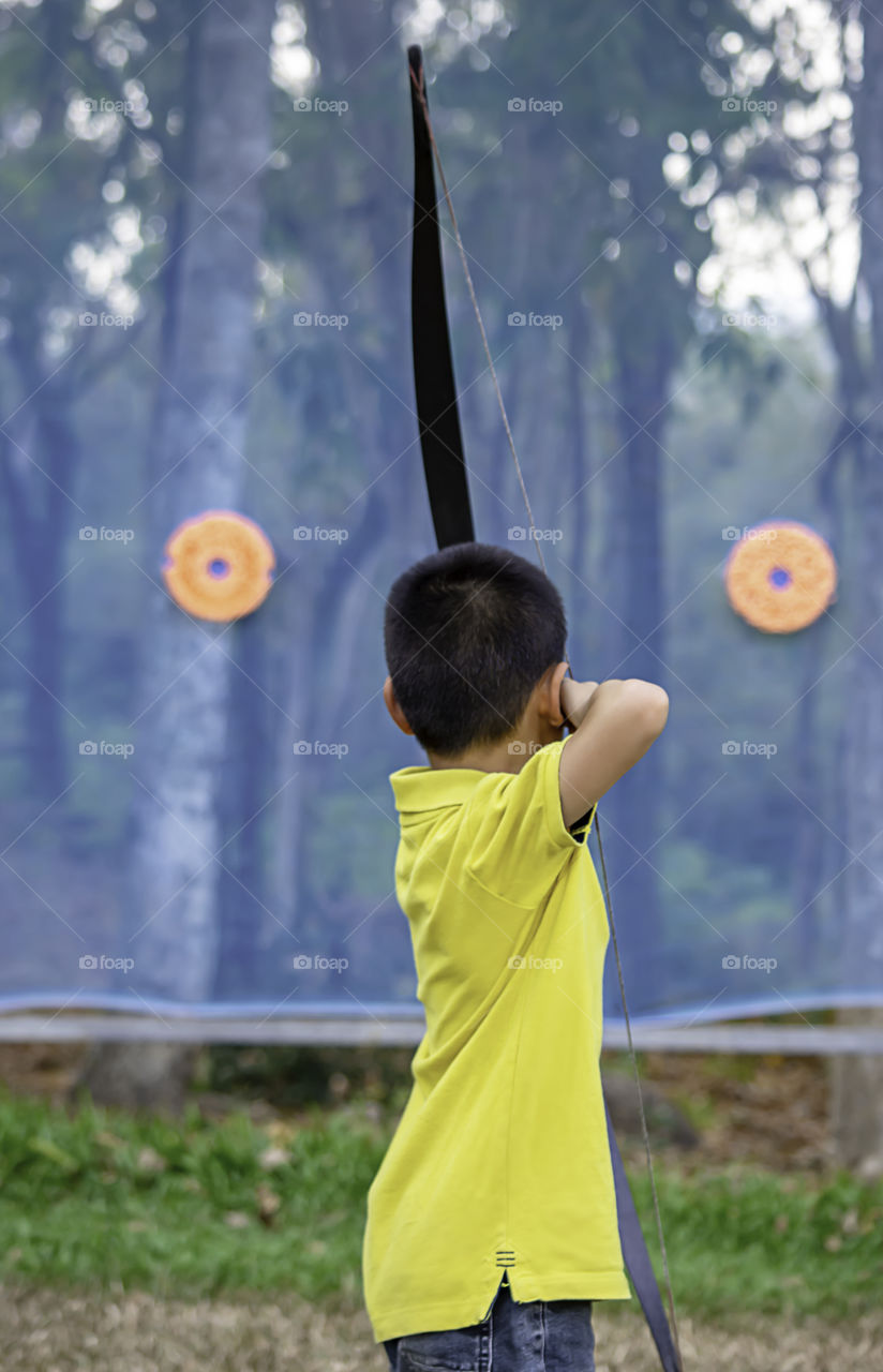 Asian boys are archery in camp adventure.