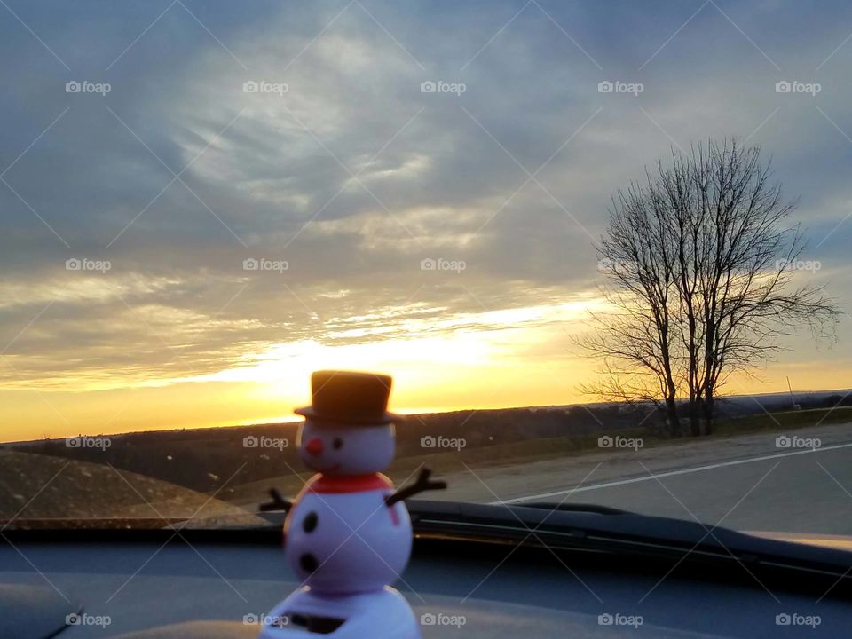 Frosty sitting on our dash in our car.  On another road trip watching the sunset.