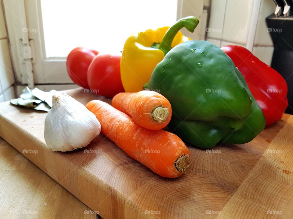 fresh vegetables on cutting board in front of Window
