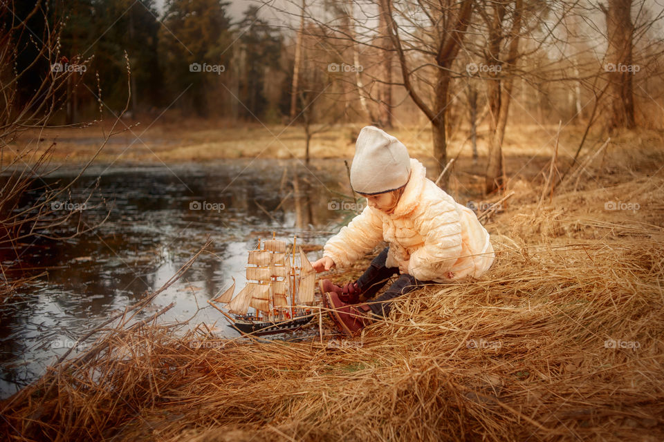 Little girl with ship toy in spring park