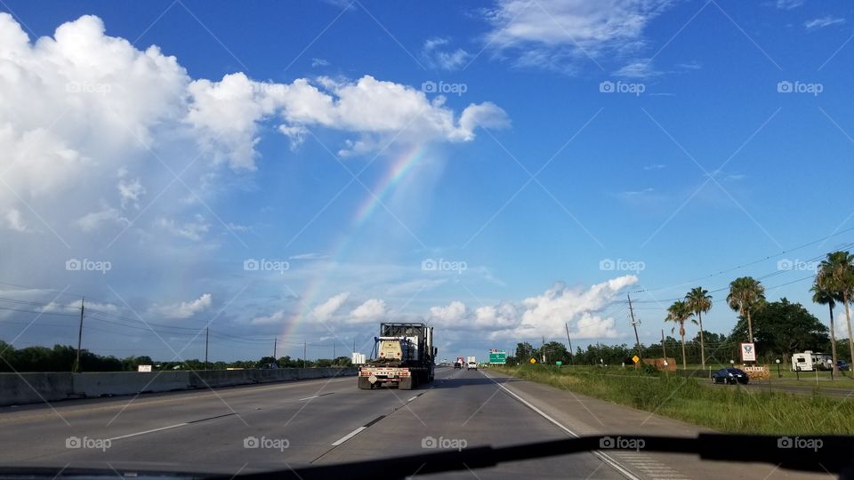 A rainbow above a highway street.