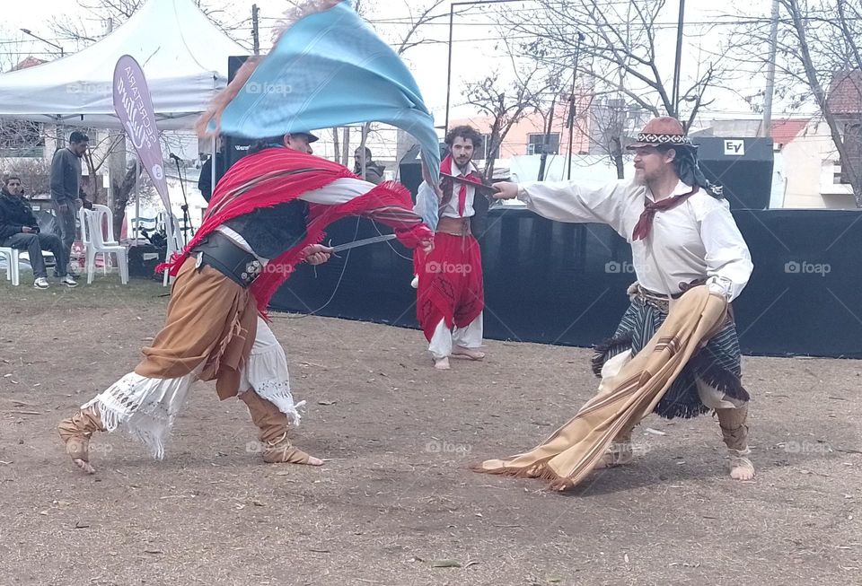 pelea entre gauchos con ponchos y facón en una parque