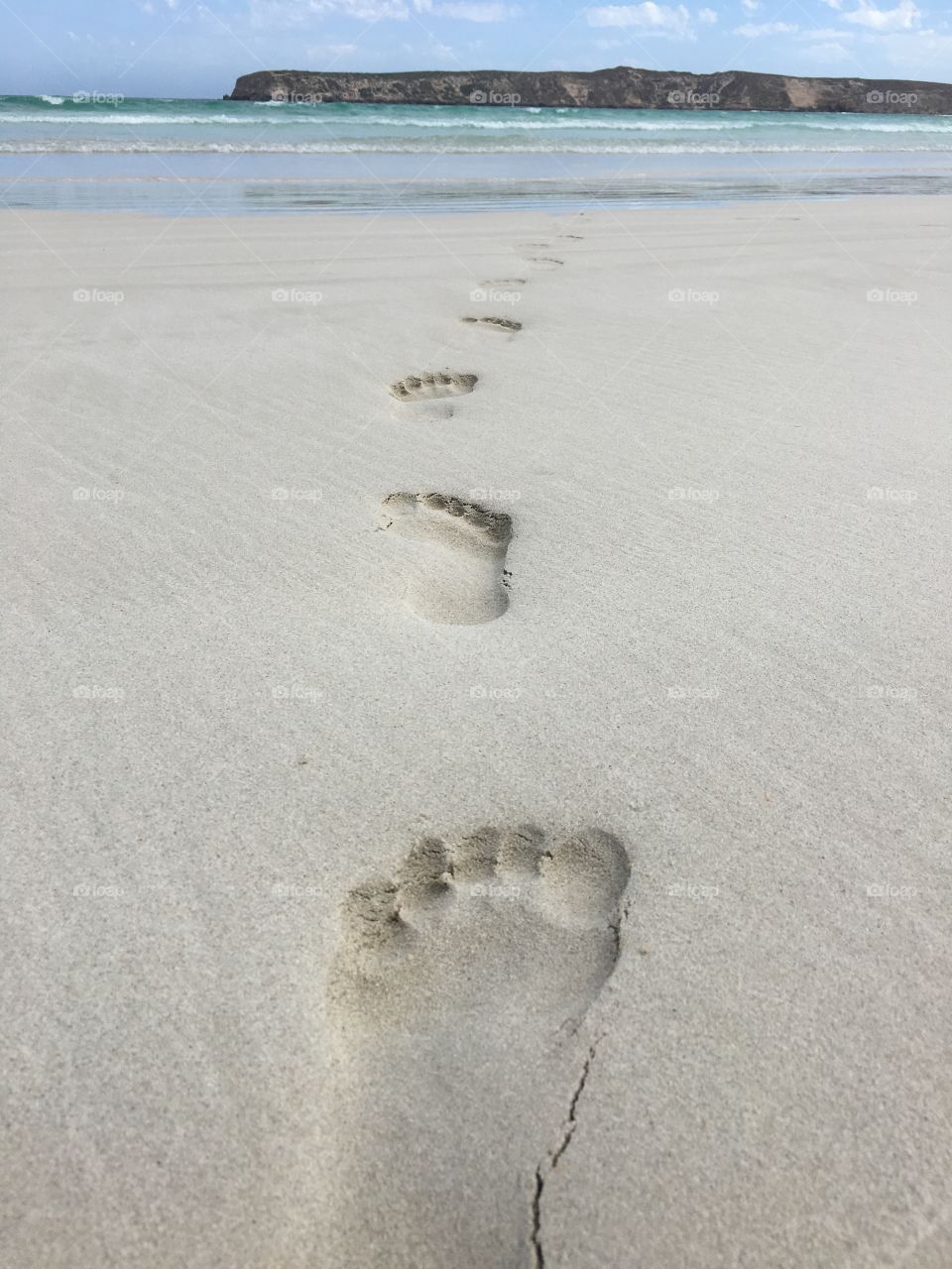 Footprints in the sand on remote beach