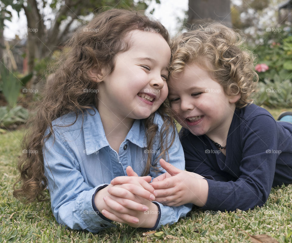 Two sibling lying on grass