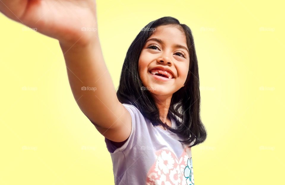 girl with an emotion of joy extending her hand, on a yellow background