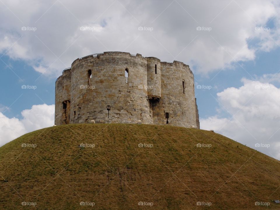 Clifford’s Tower, a local stone landmark in York in England, sits majestically on top of a hill on a sunny day. 