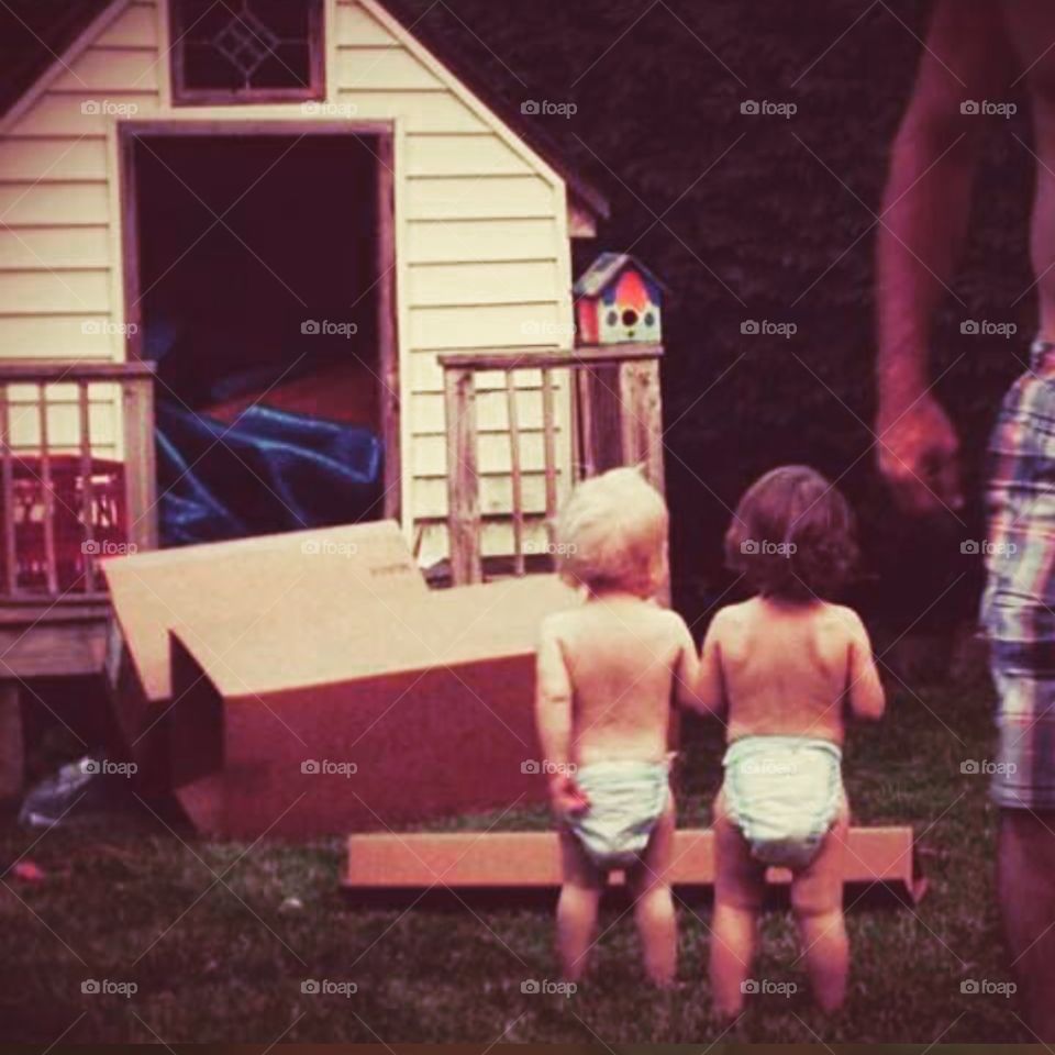 Two toddlers excited about the playhouse their Papa made for them. 