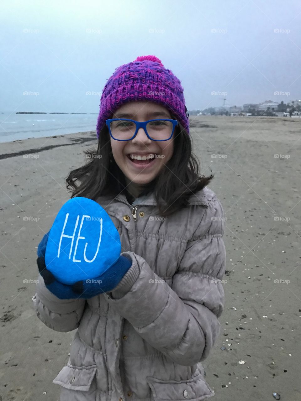 Happy girl holding colored pebble stone in hand