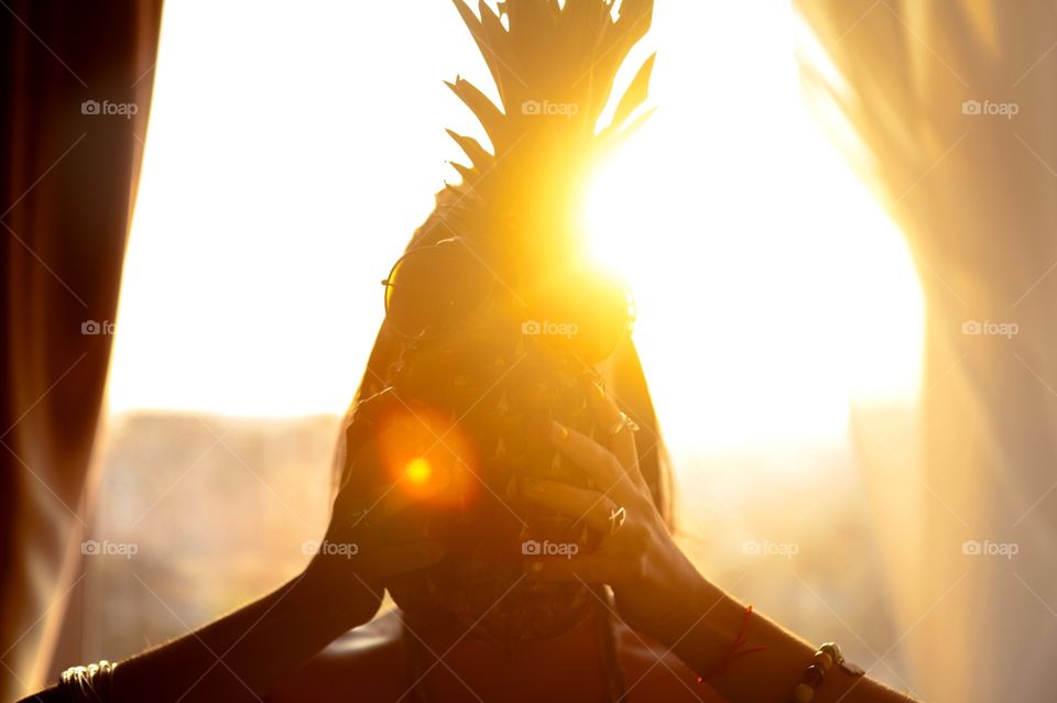 Woman with pineapple in sunset