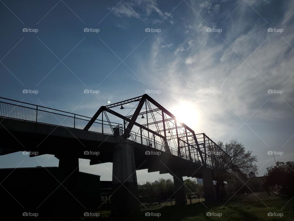 Sunset silhouettes and shadows by a historic bridge.