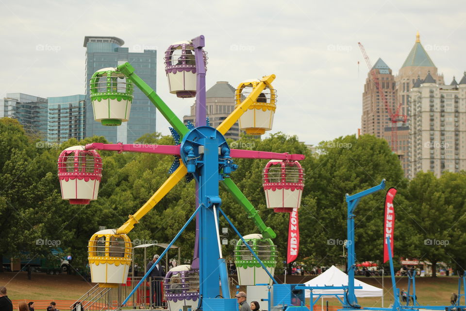 City park in summer times. Cityscape in background while the children park Ferris wheel in front. Picture taken while dogwood festival in Atlanta 