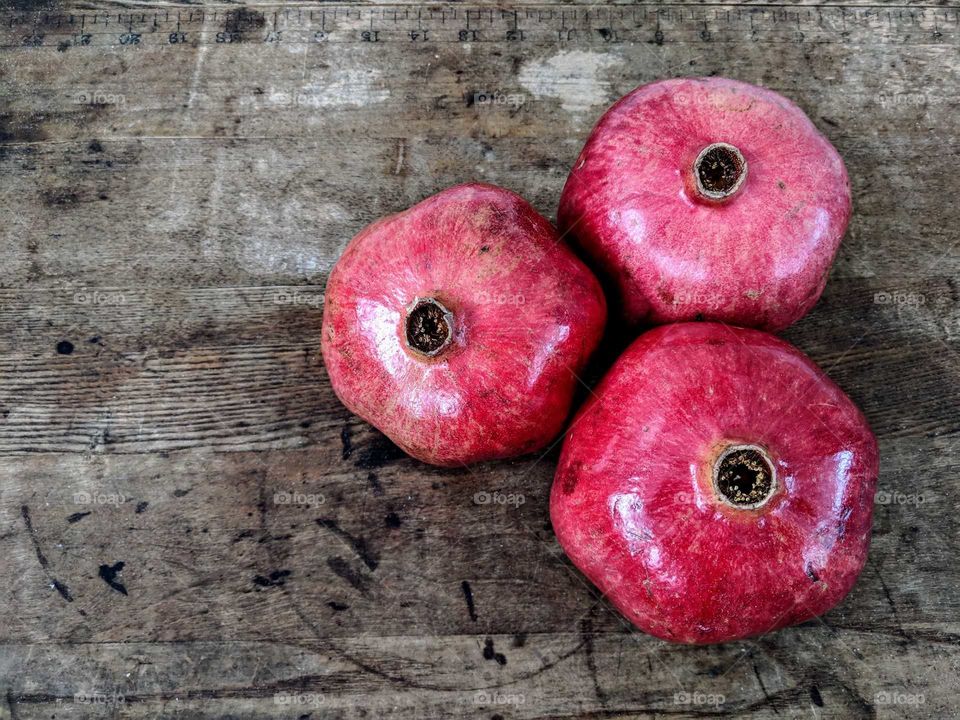 three pomegranates on a wooden table