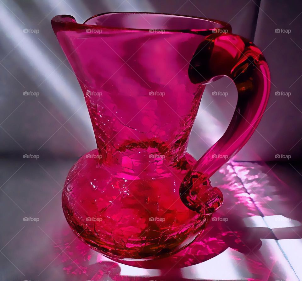 Magenta antique glass pitcher in shadows and sunlight.