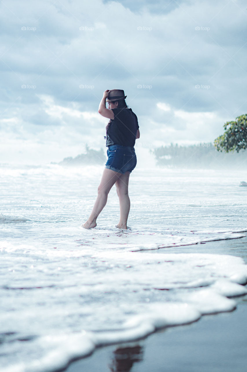 Girl enjoying the waves of the sea on the beach. Photography edited in soft colors