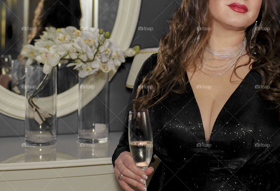 A girl in beautiful jewelry in an evening dress and with a glass of champagne.