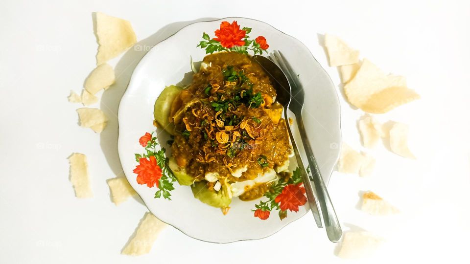 Traditional cuisine typical of Central Java, Indonesia. Dreadlocked tofu plus peanut sauce and rice cakes on the table in bird's eye view