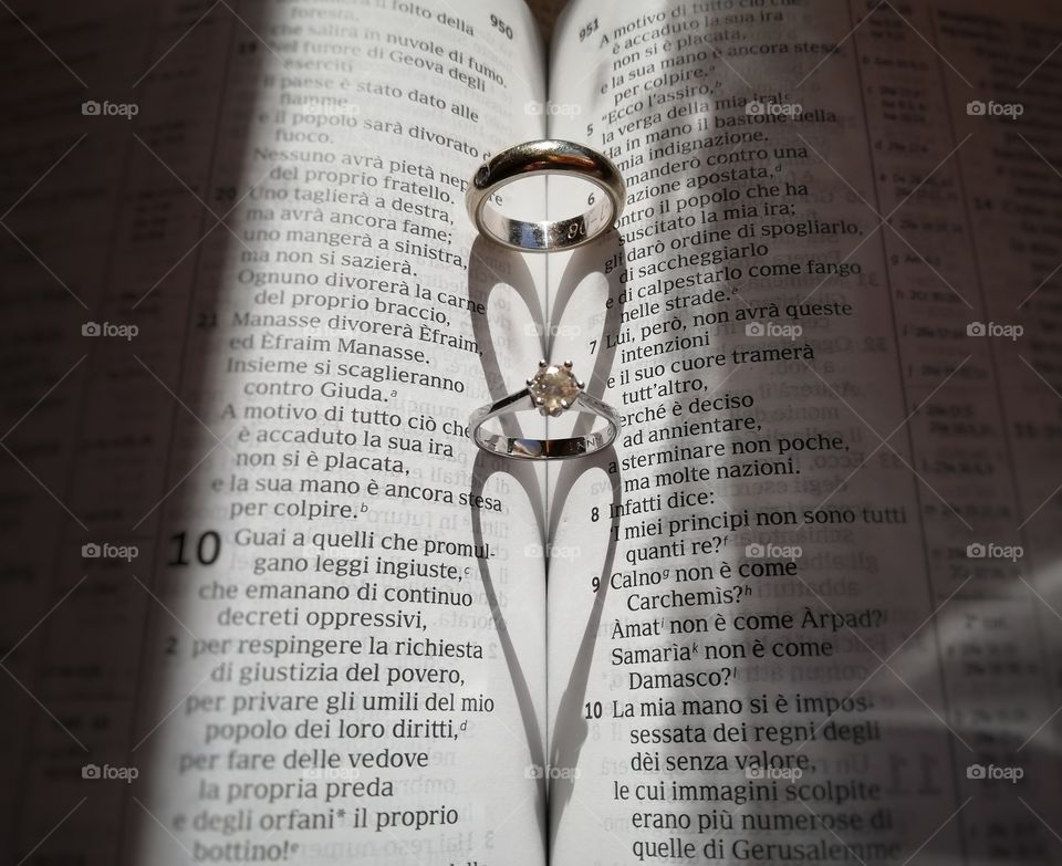 Wedding ring on the Bible forms the shadows of a heart