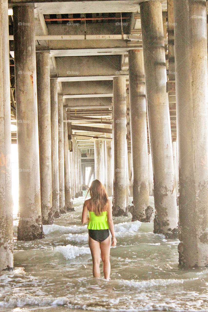 Rear view of woman standing underneath pier